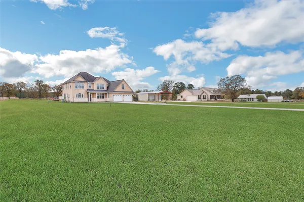 a view of a house with a big yard and large trees