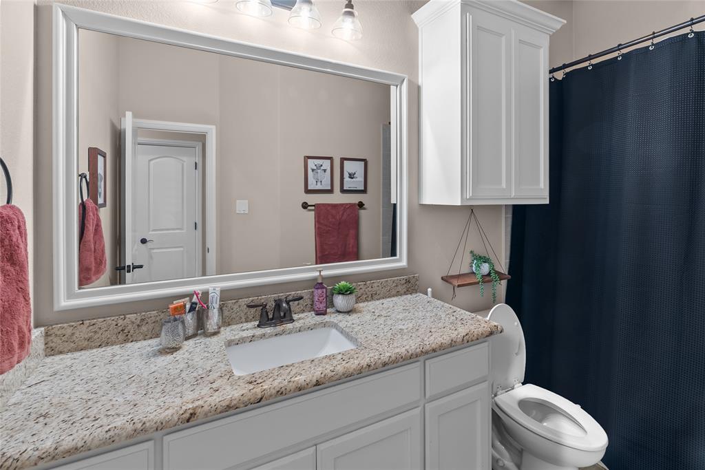 222 Rees Avenue Godley, TX 76044 - Photo 16 of 25 a bathroom with a granite countertop sink vanity mirror and toilet