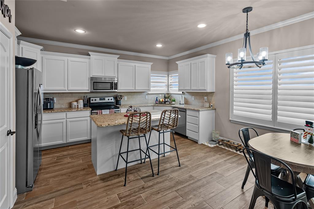 222 Rees Avenue Godley, TX 76044 - Photo 10 of 25 a kitchen with stainless steel appliances a dining table chairs stove refrigerator and microwave