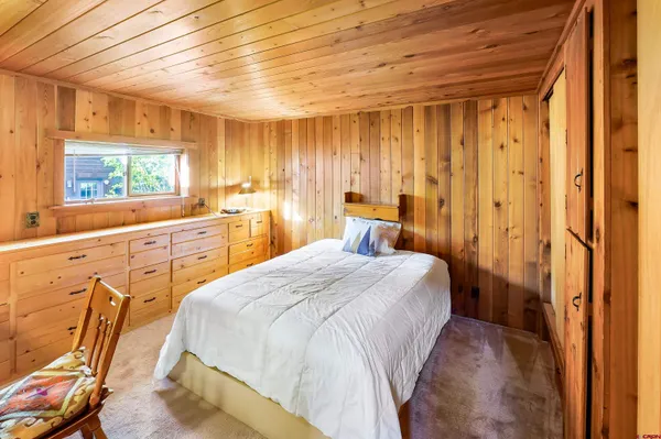 a spacious bedroom with a bed and a dresser next to a window