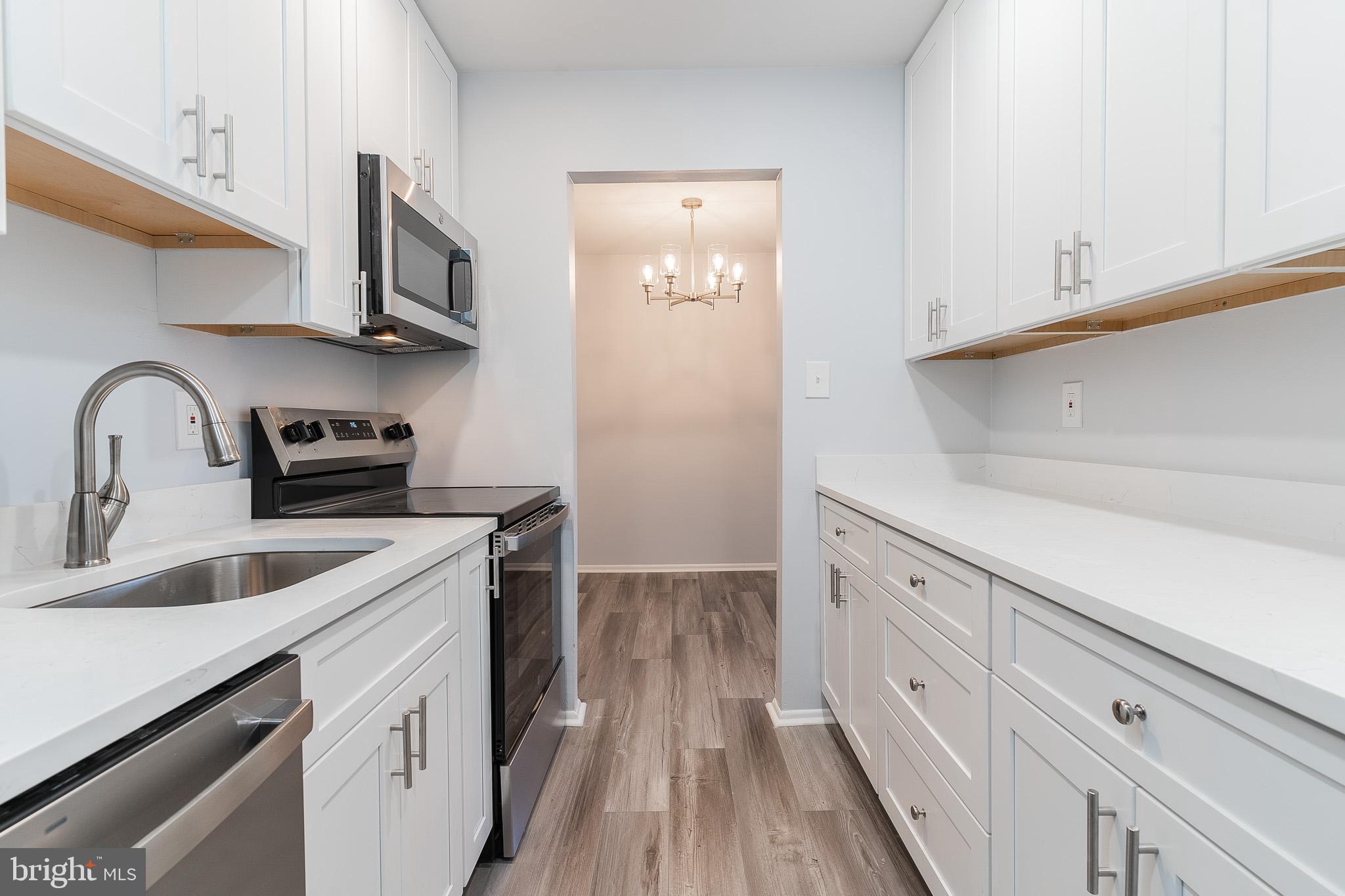 8708 Village Square Drive Alexandria, VA 22309 - Photo 22 of 46 a kitchen with stainless steel appliances granite countertop a sink and dishwasher a stove top oven with wooden floor