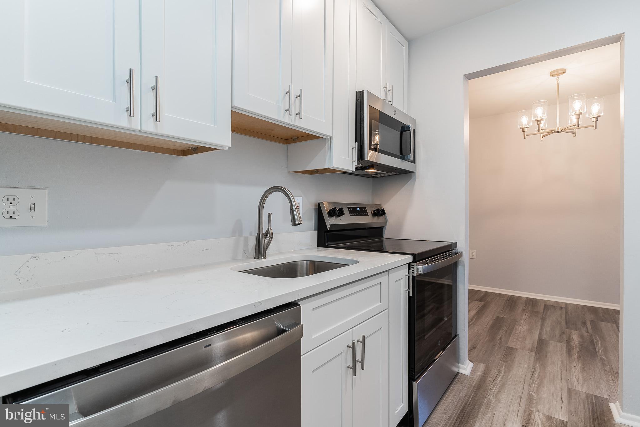 8708 Village Square Drive Alexandria, VA 22309 - Photo 24 of 46 a kitchen with stainless steel appliances granite countertop a sink a stove and microwave with wooden floor
