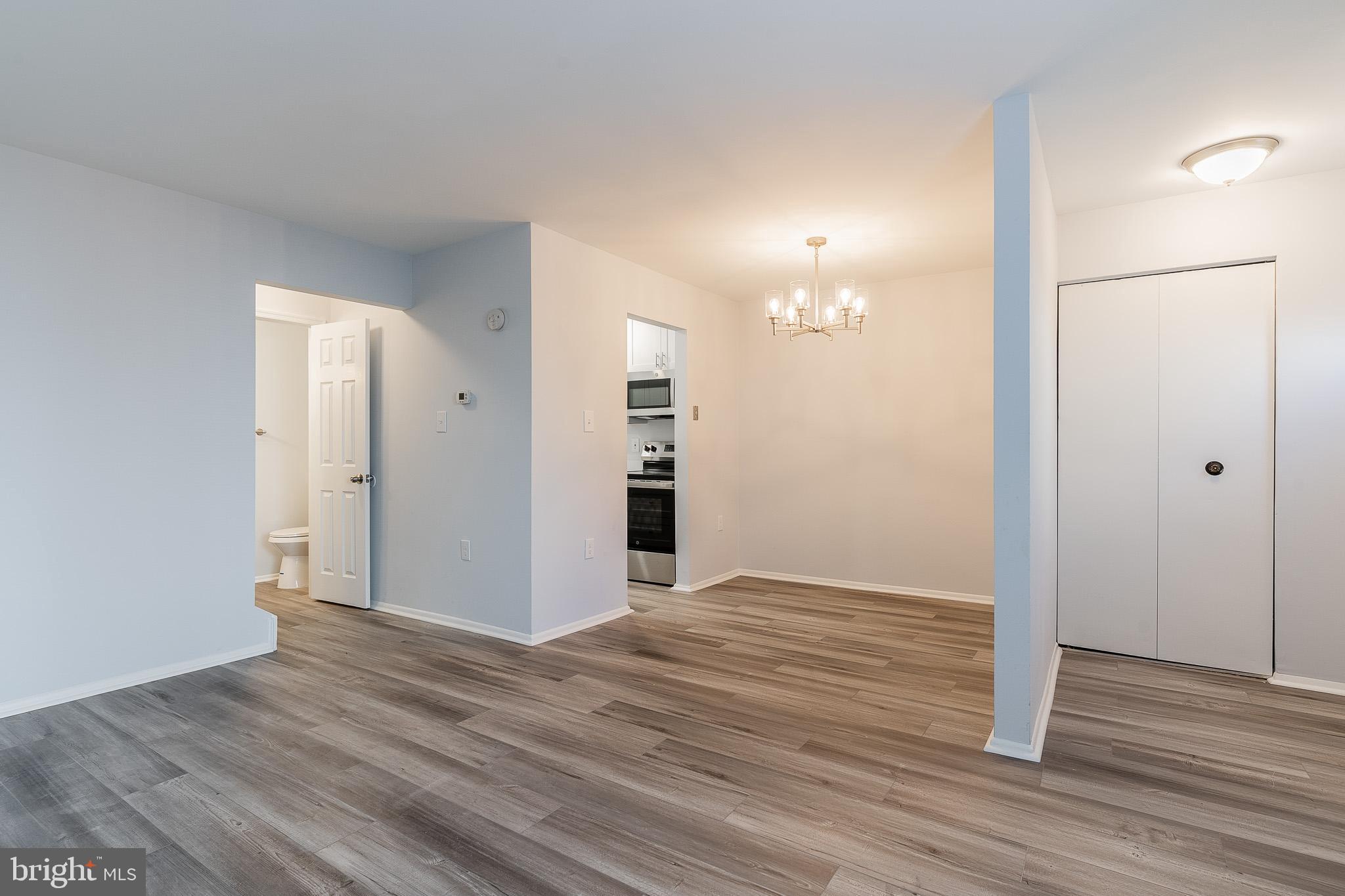 8708 Village Square Drive Alexandria, VA 22309 - Photo 9 of 46 an empty room with wooden floor and way to kitchen