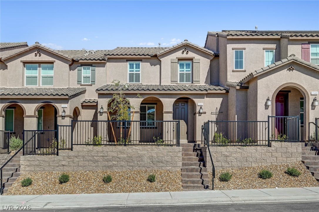 View of front of home with a tile roof, covered porch, stairs, and stucco siding
