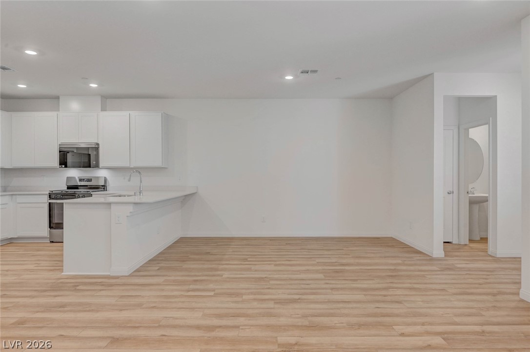 3548 Dimora Street Henderson, NV 89044 - Photo 12 of 40 Kitchen featuring light wood-style flooring, baseboards, and appliances with stainless steel finishes