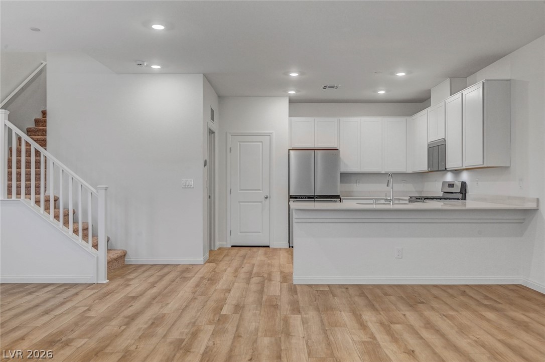 3548 Dimora Street Henderson, NV 89044 - Photo 14 of 40 Kitchen with a peninsula, light wood-style floors, stainless steel appliances, and recessed lighting
