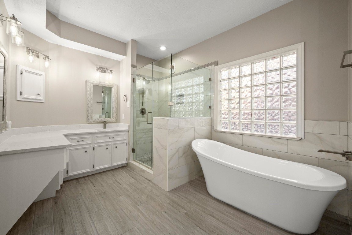 8222 Redchurch Drive Spring, TX 77379 - Photo 12 of 36 a spacious bathroom with a double vanity sink a large mirror a bathtub and next to a window