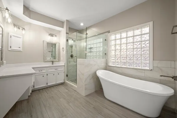 a bathroom with a bathtub a double vanity sink a window and a shower