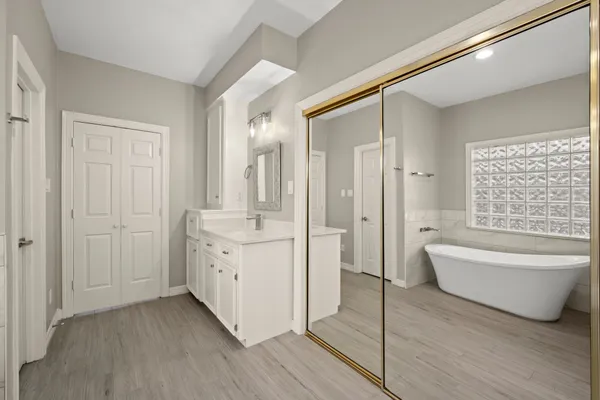 a bathroom with a double vanity sink a mirror and a bathtub