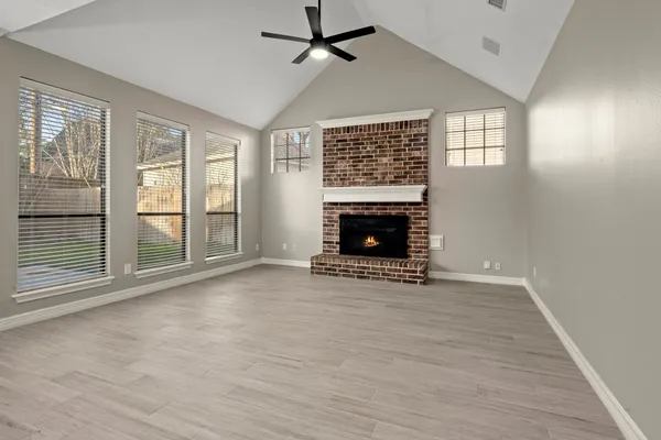 wooden floor fireplace and windows in an empty room