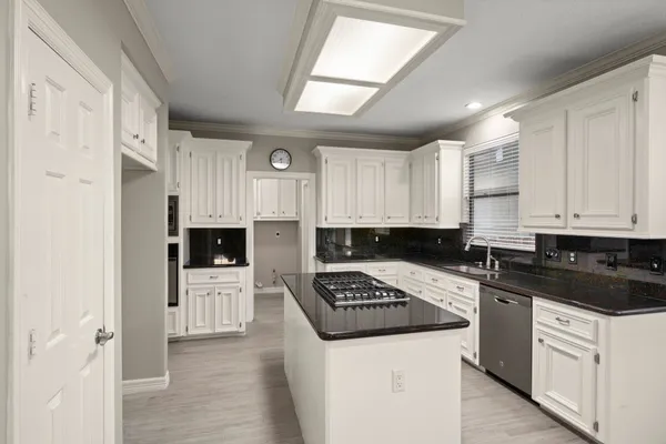 a kitchen with granite countertop a sink a stove and cabinets
