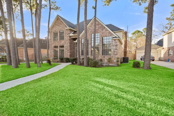 a view of a brick house with a big yard and large trees