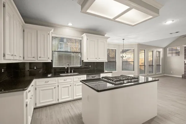 a kitchen with stainless steel appliances granite countertop a stove a sink and white cabinets