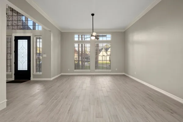 a view of an empty room with wooden floor and a window