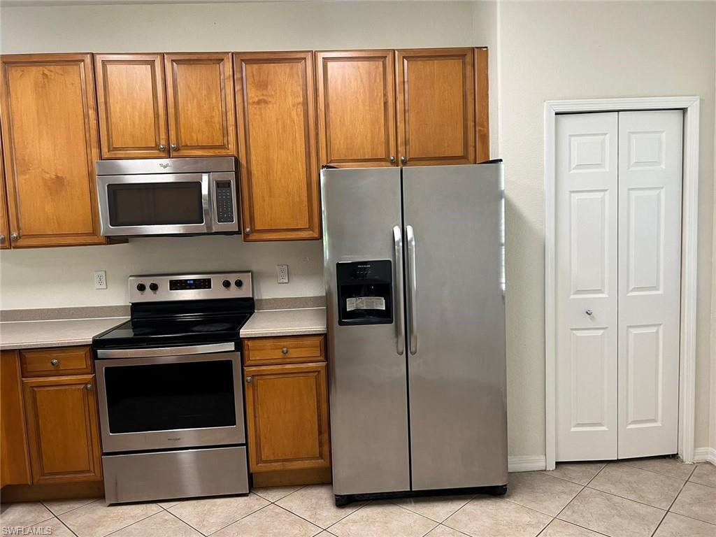 7515 Bristol Circle Naples, FL 34120 - Photo 11 of 42 a kitchen with granite countertop a refrigerator stove and microwave