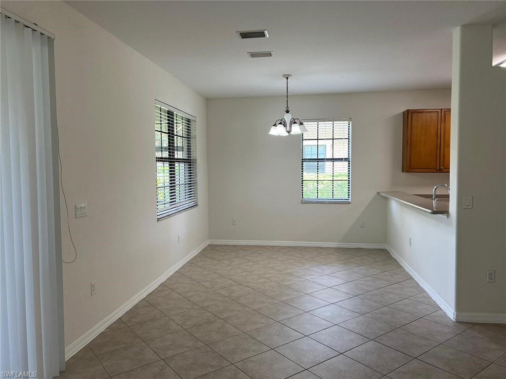 7515 Bristol Circle Naples, FL 34120 - Photo 15 of 42 an empty room with windows and chandelier fan