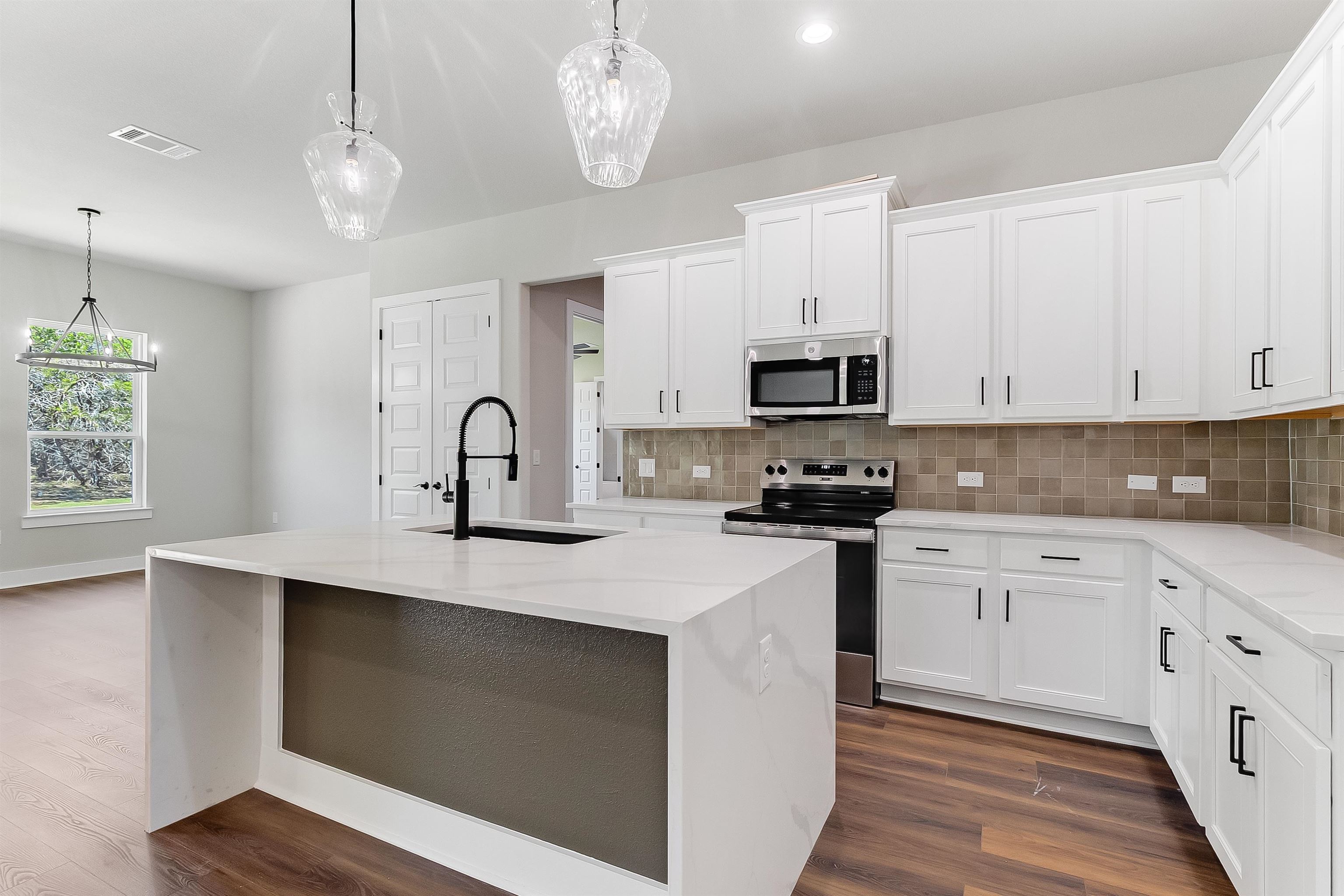 118 Rosebud Rnch Road Bertram, TX 78605 - Photo 3 of 23 a kitchen with stainless steel appliances granite countertop a sink dishwasher a stove and a microwave oven with wooden floor