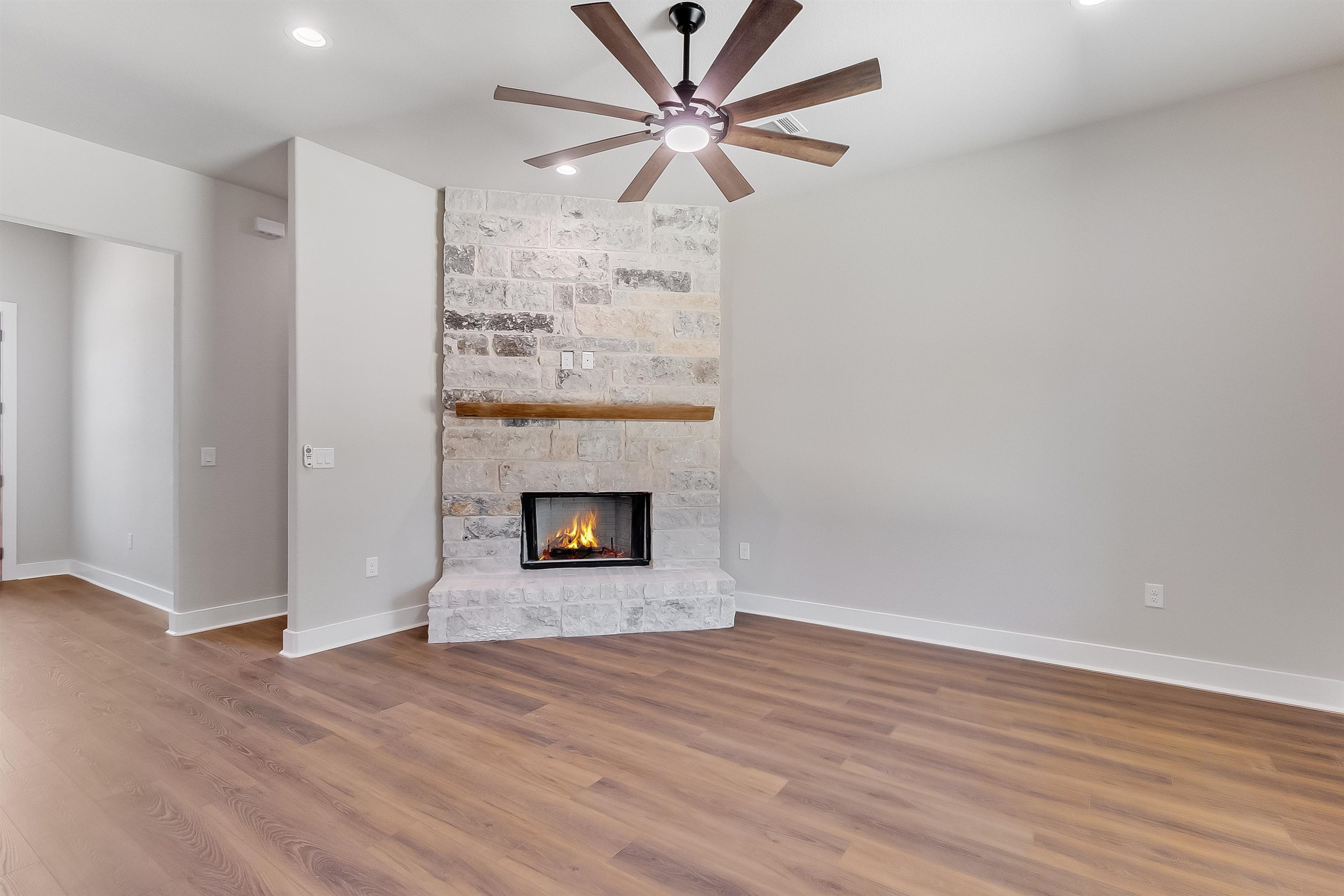 118 Rosebud Rnch Road Bertram, TX 78605 - Photo 6 of 23 an empty room with a fireplace and a ceiling fan
