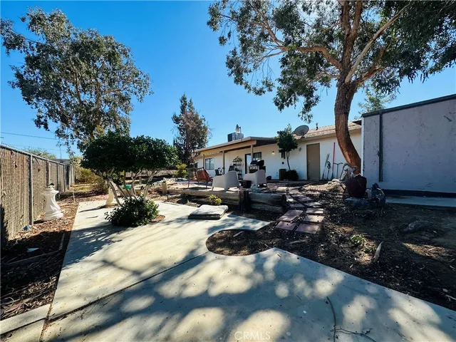 a backyard of a house with table and chairs under an umbrella