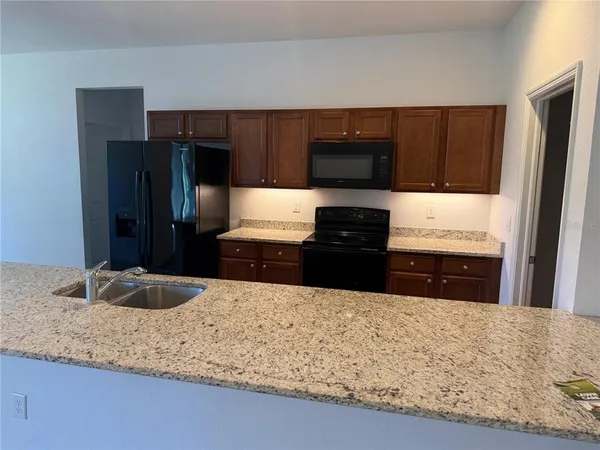 a kitchen with kitchen island granite countertop a refrigerator and a sink
