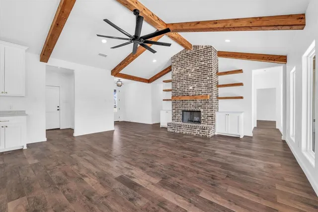 a view of an empty room with wooden floor and a fireplace