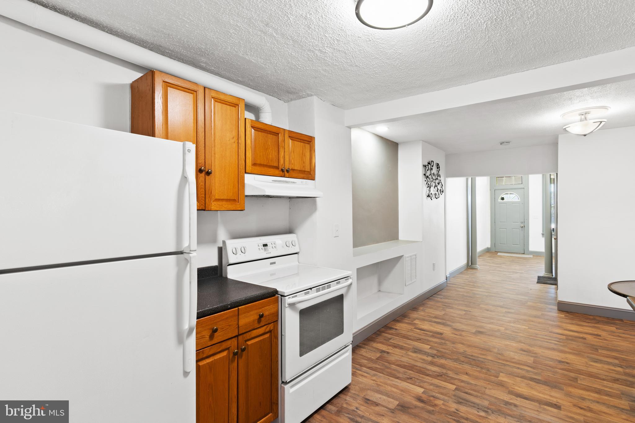 941 Brunswick Street Baltimore, MD 21223 - Photo 12 of 35 a kitchen with stainless steel appliances granite countertop a refrigerator a stove and a sink with wooden floors