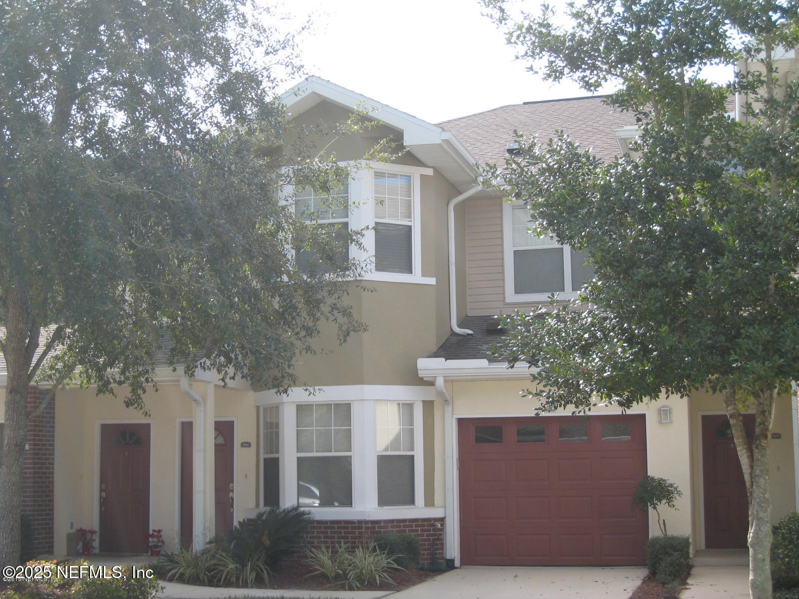 a front view of a house with plants and trees