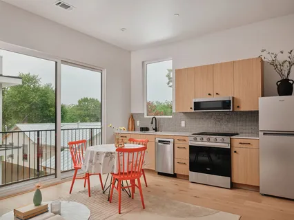a kitchen with a refrigerator a stove a sink wooden floor and a dining table
