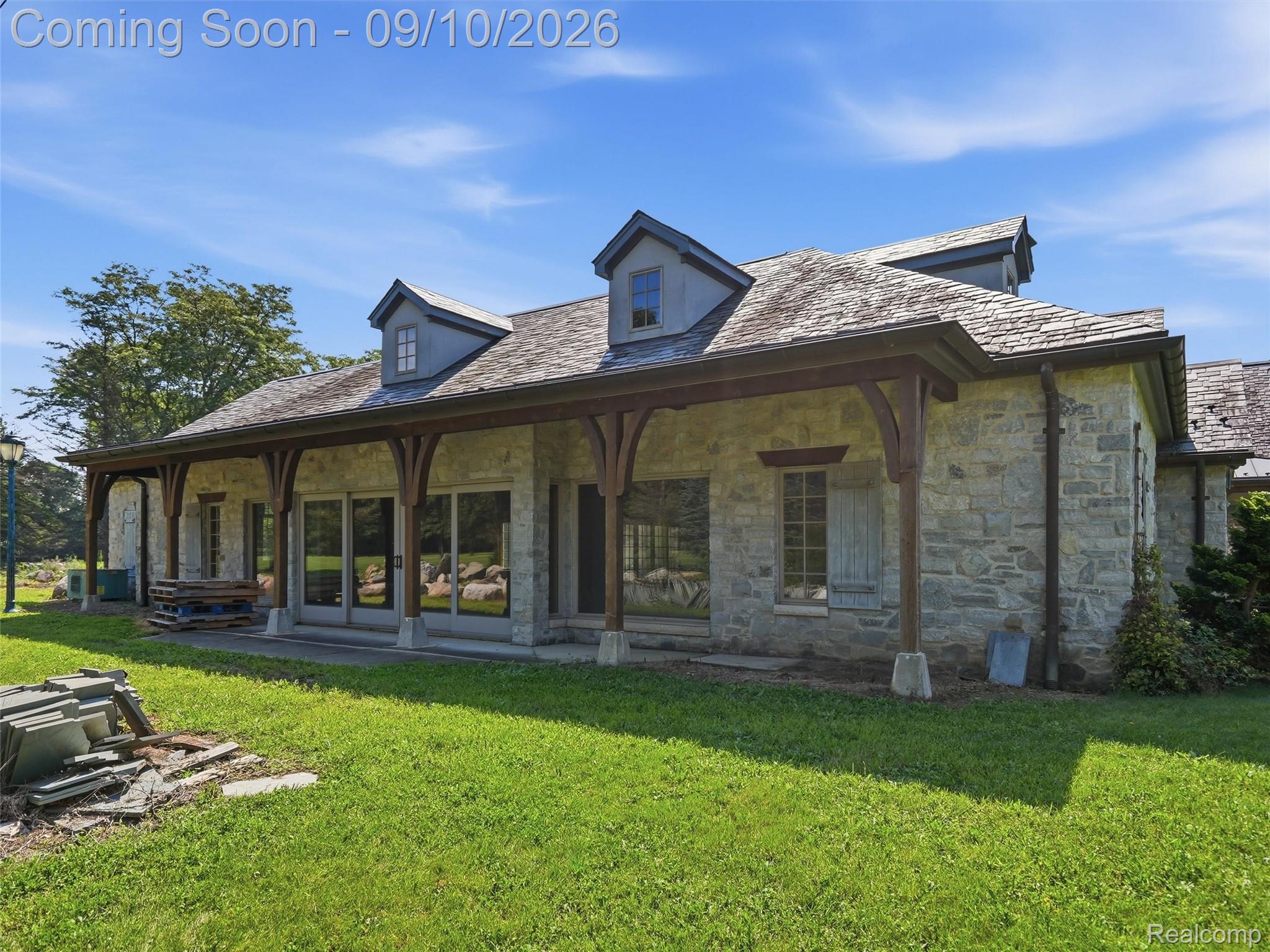 61400 Romeo Plank Road Ray, MI 48096 - Photo 78 of 99 Stone exterior with a covered porch featuring exposed wood beams and supports