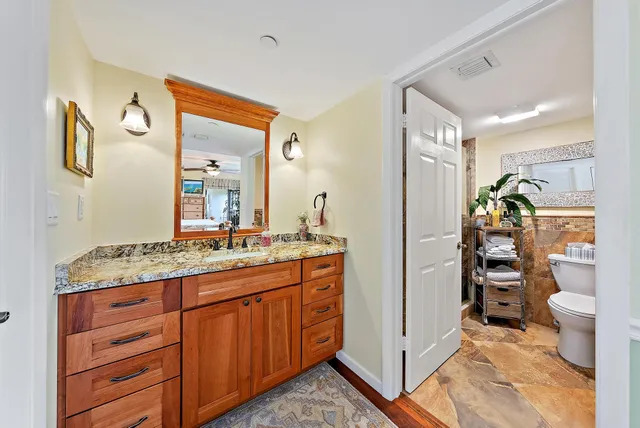 a bathroom with a granite countertop sink a toilet and shower