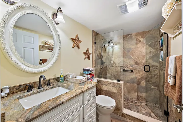 a bathroom with a granite countertop sink mirror vanity and toilet
