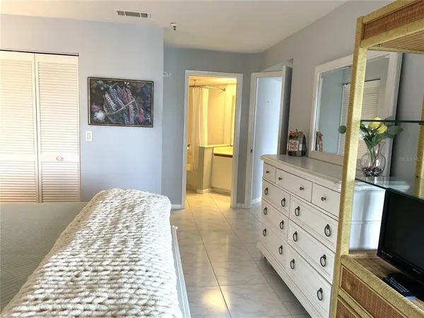 a bedroom with a bed and a flat tv screen on dresser
