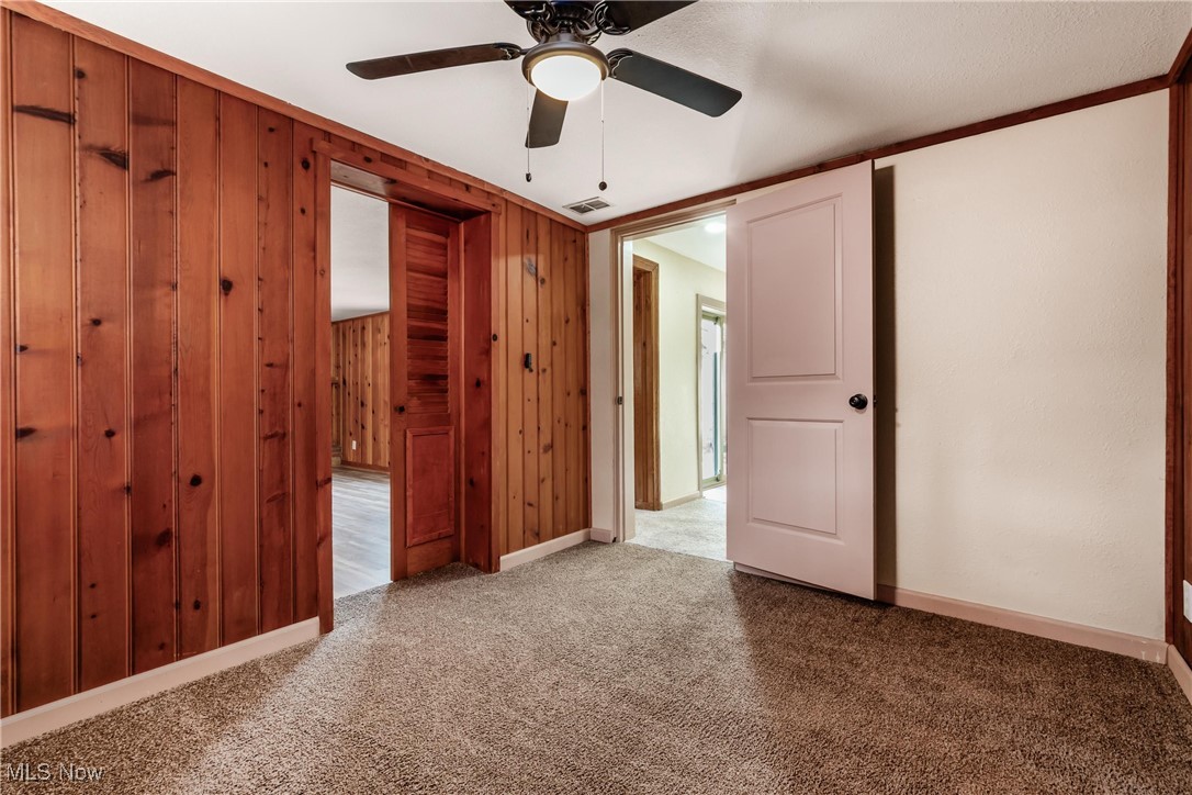724 Garden Road Zanesville, OH 43701 - Photo 19 of 22 Unfurnished bedroom featuring carpet floors, wood walls, a ceiling fan, and crown molding
