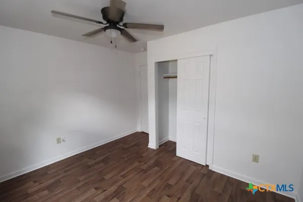 a view of a room with wooden floor and a ceiling fan