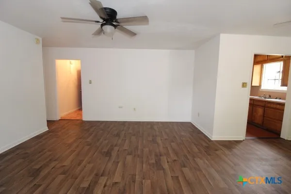 a view of a livingroom with wooden floor and a ceiling fan
