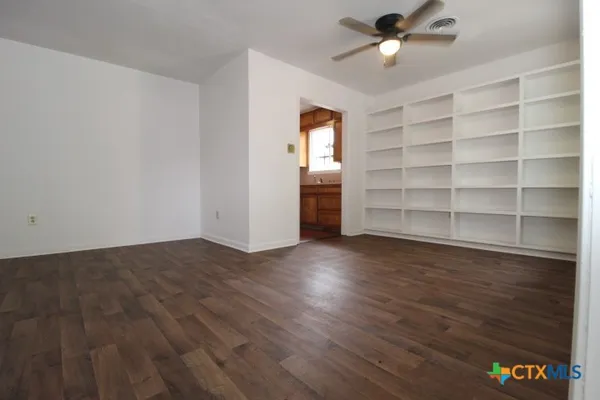 a view of an empty room with a window and wooden floor