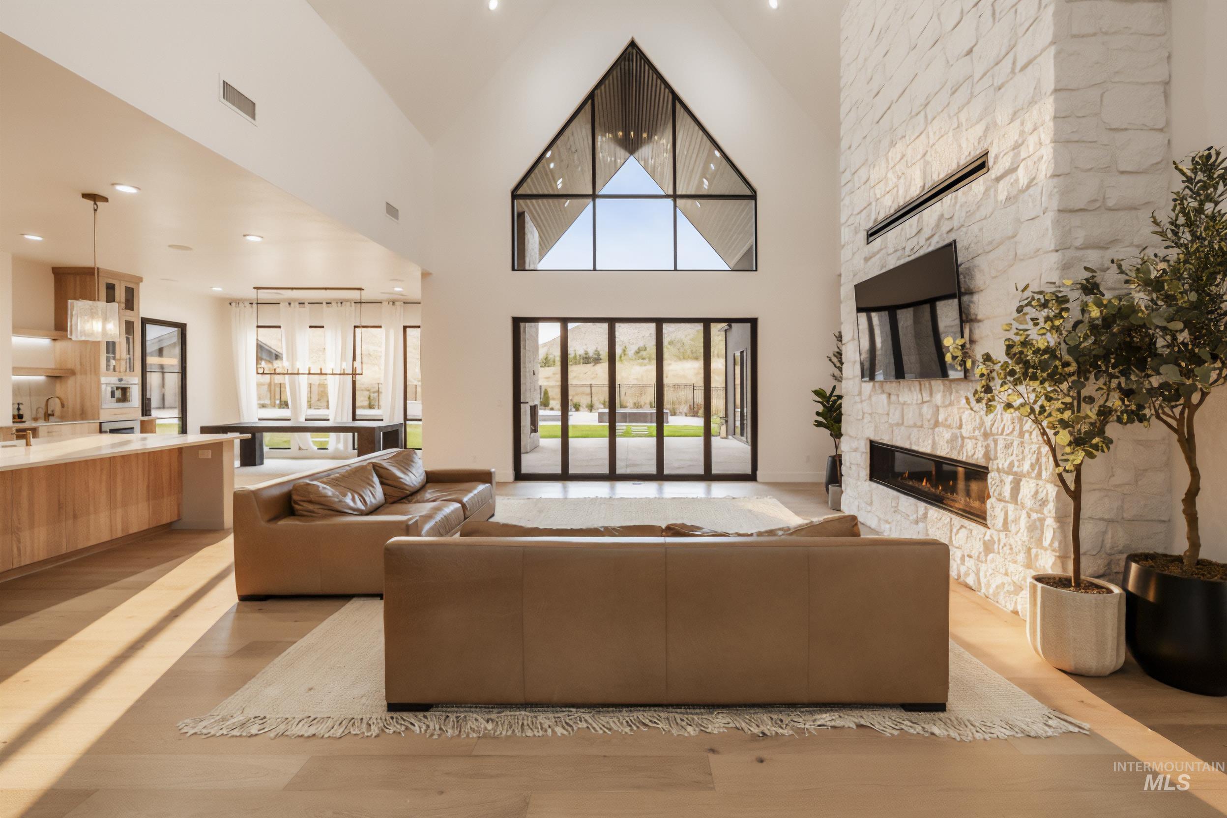 6162 North High Valley Way Boise, ID 83714 - Photo 10 of 50 Living room with light wood finished floors, recessed lighting, a stone fireplace, and a towering ceiling