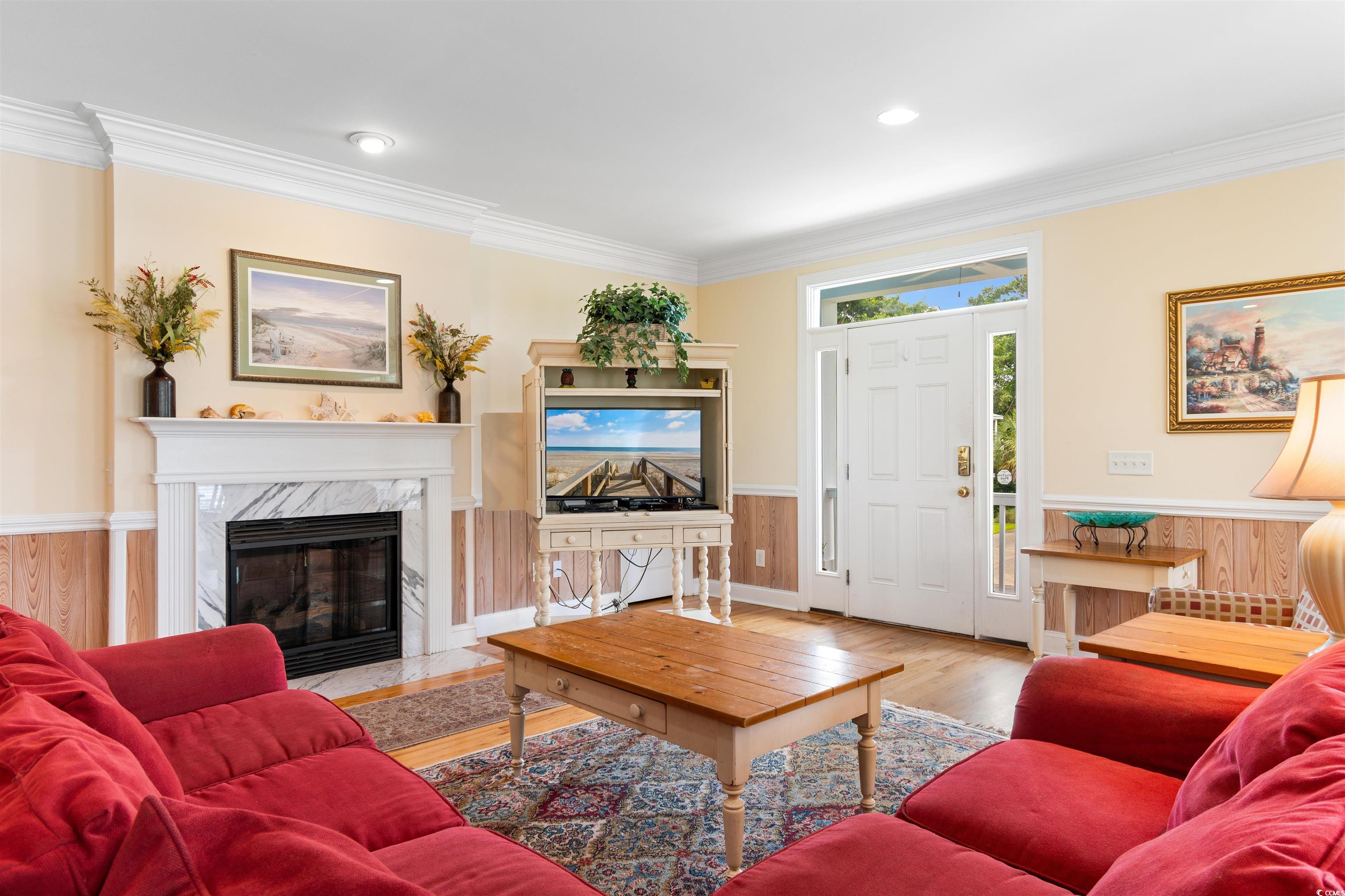 141 Cayman Loop Pawleys Island, SC 29585 - Photo 12 of 40 Living room featuring crown molding, wood finished floors, a fireplace, and wainscoting