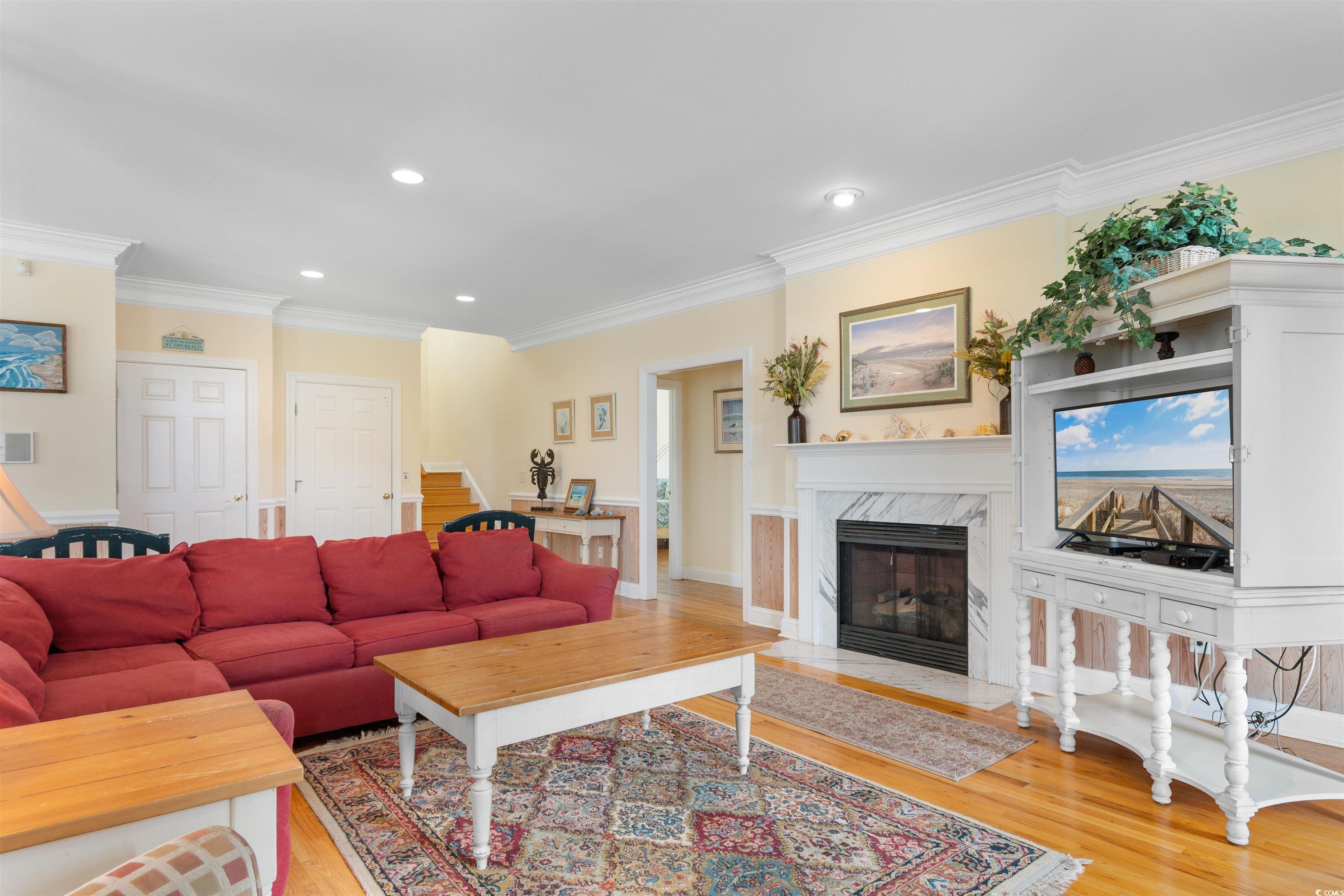 141 Cayman Loop Pawleys Island, SC 29585 - Photo 13 of 40 Living room featuring light wood-style floors, ornamental molding, recessed lighting, a high end fireplace, and stairway