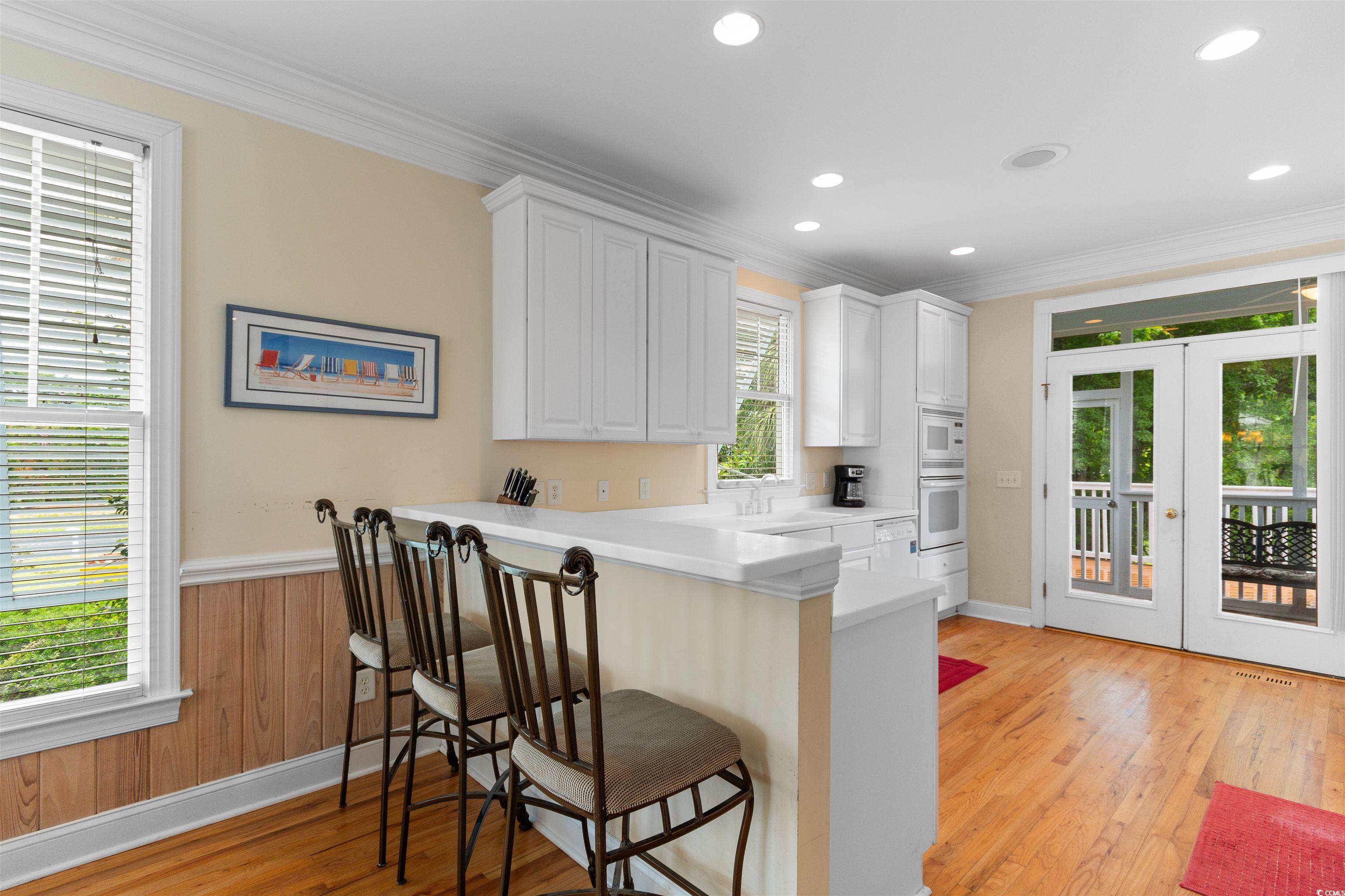 141 Cayman Loop Pawleys Island, SC 29585 - Photo 4 of 40 Kitchen with white appliances, ornamental molding, a kitchen bar, french doors, and white cabinets