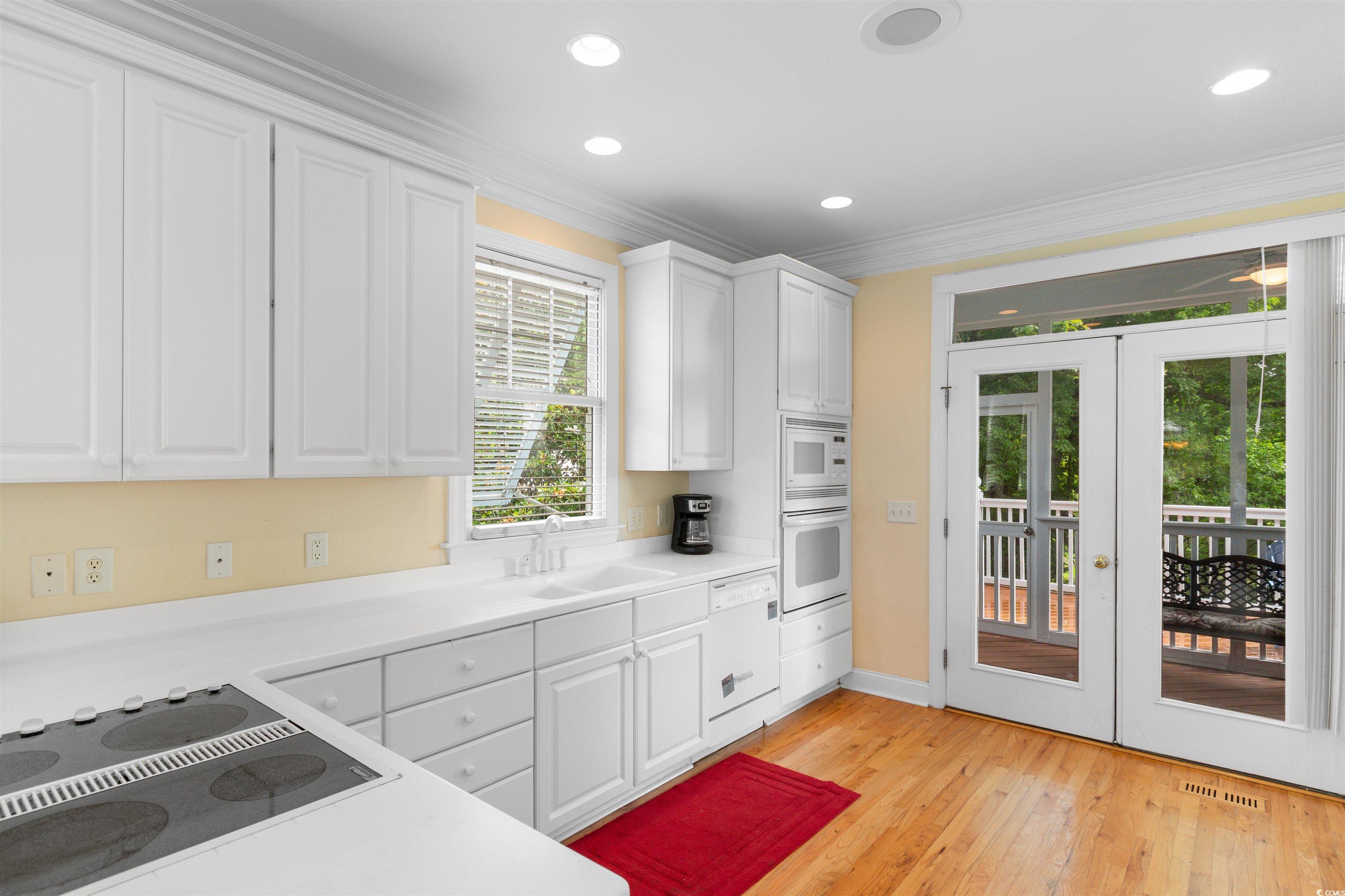 141 Cayman Loop Pawleys Island, SC 29585 - Photo 5 of 40 Kitchen with white appliances, french doors, a sink, white cabinetry, and ornamental molding