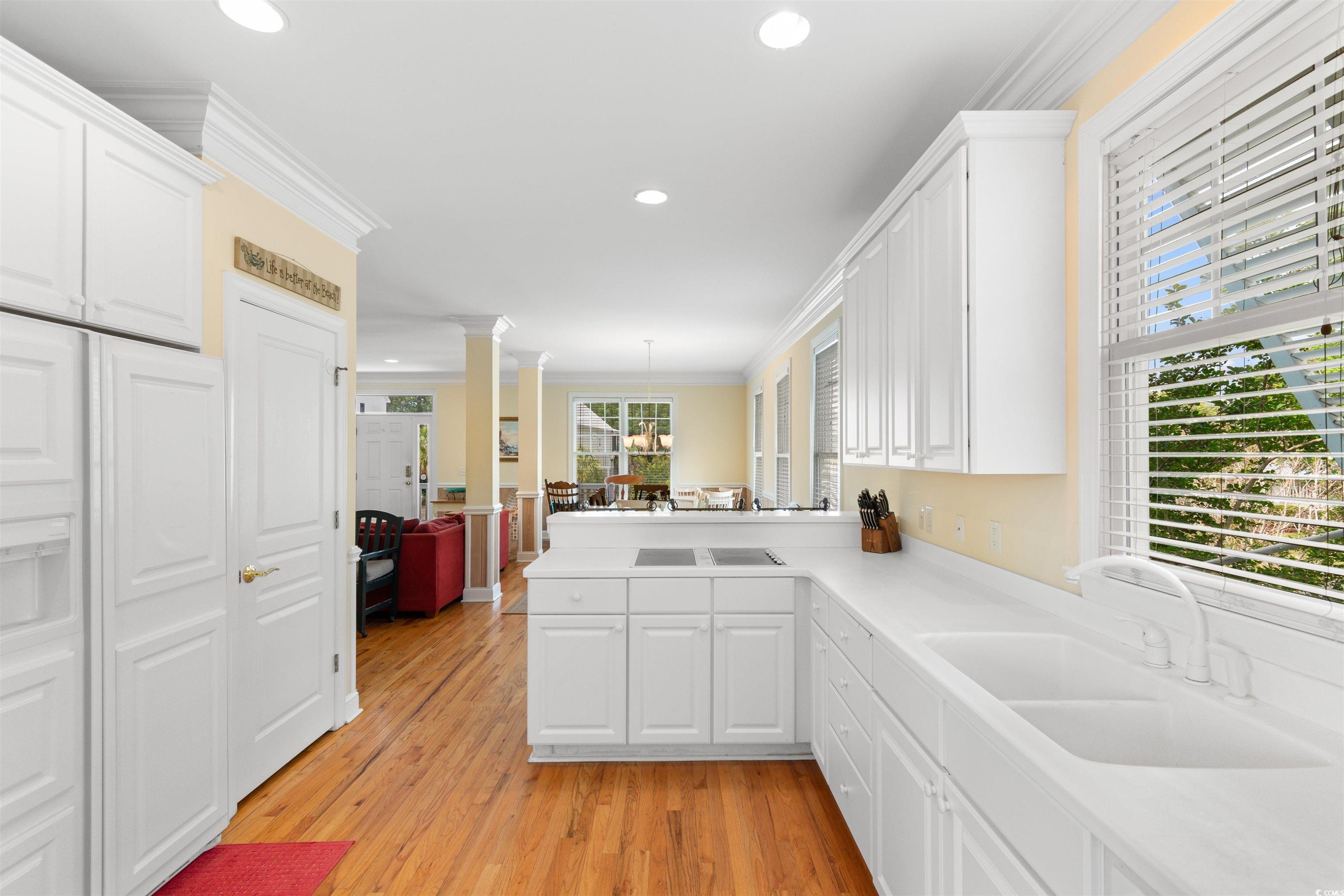 141 Cayman Loop Pawleys Island, SC 29585 - Photo 7 of 40 Kitchen with a sink, crown molding, white cabinetry, ornate columns, and recessed lighting
