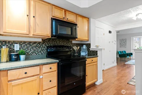 a kitchen with granite countertop white cabinets and black appliances