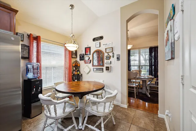 a kitchen with stainless steel appliances a dining table chairs refrigerator and sink