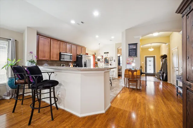 a large kitchen with cabinets chairs and stainless steel appliances