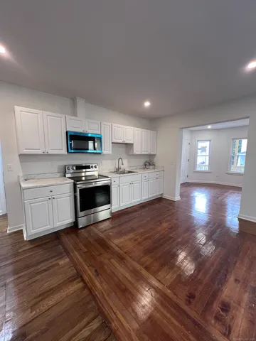 a kitchen with granite countertop a stove top oven and cabinets