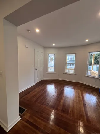 a view of an empty room with wooden floor and window
