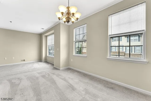 a view of an empty room with a chandelier fan and windows