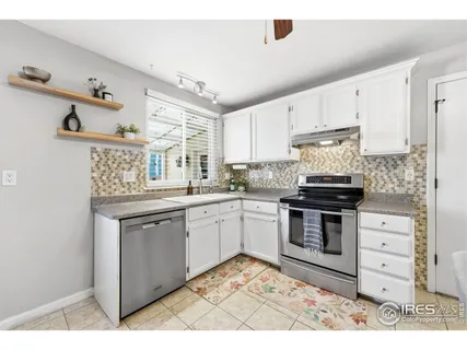 a kitchen with stainless steel appliances kitchen island granite countertop a refrigerator a stove a sink dishwasher and white cabinets with wooden floor