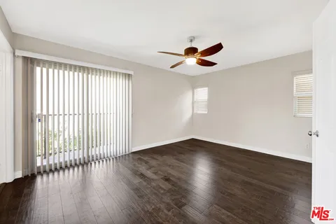 an empty room with wooden floor fan and windows
